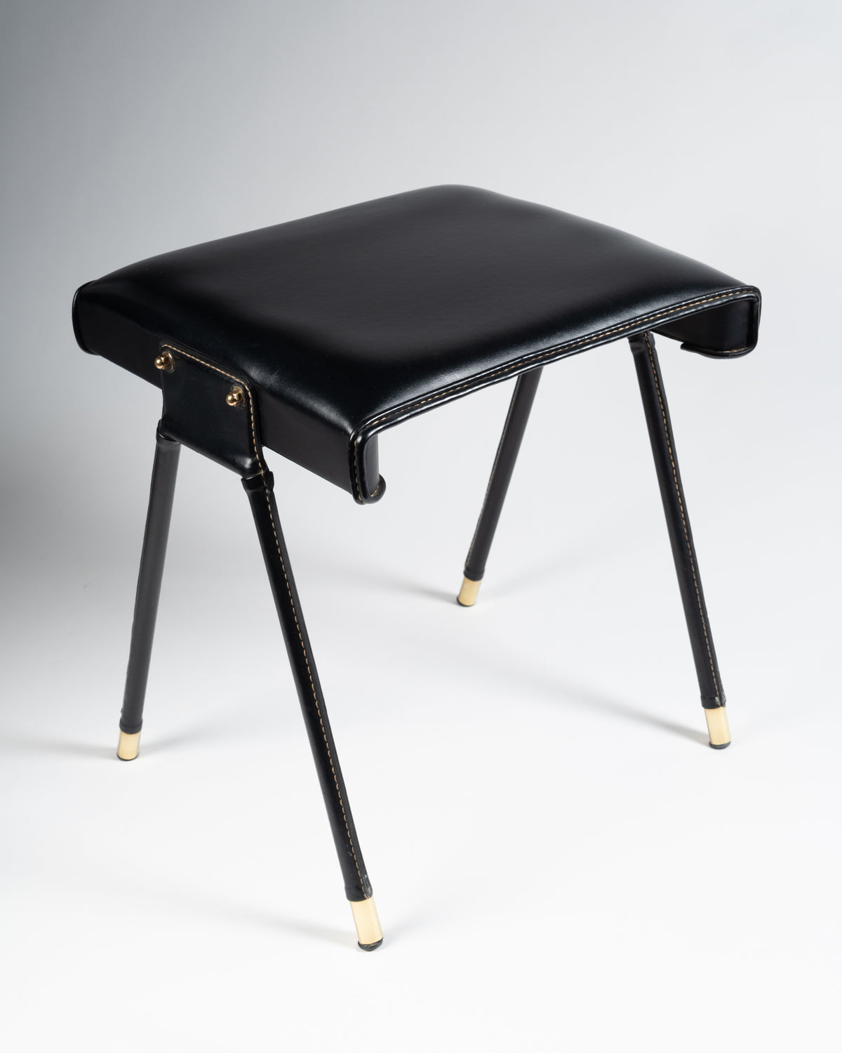 Tabouret de Jacques Adnet en skaï noir piqué sellier et laiton doré