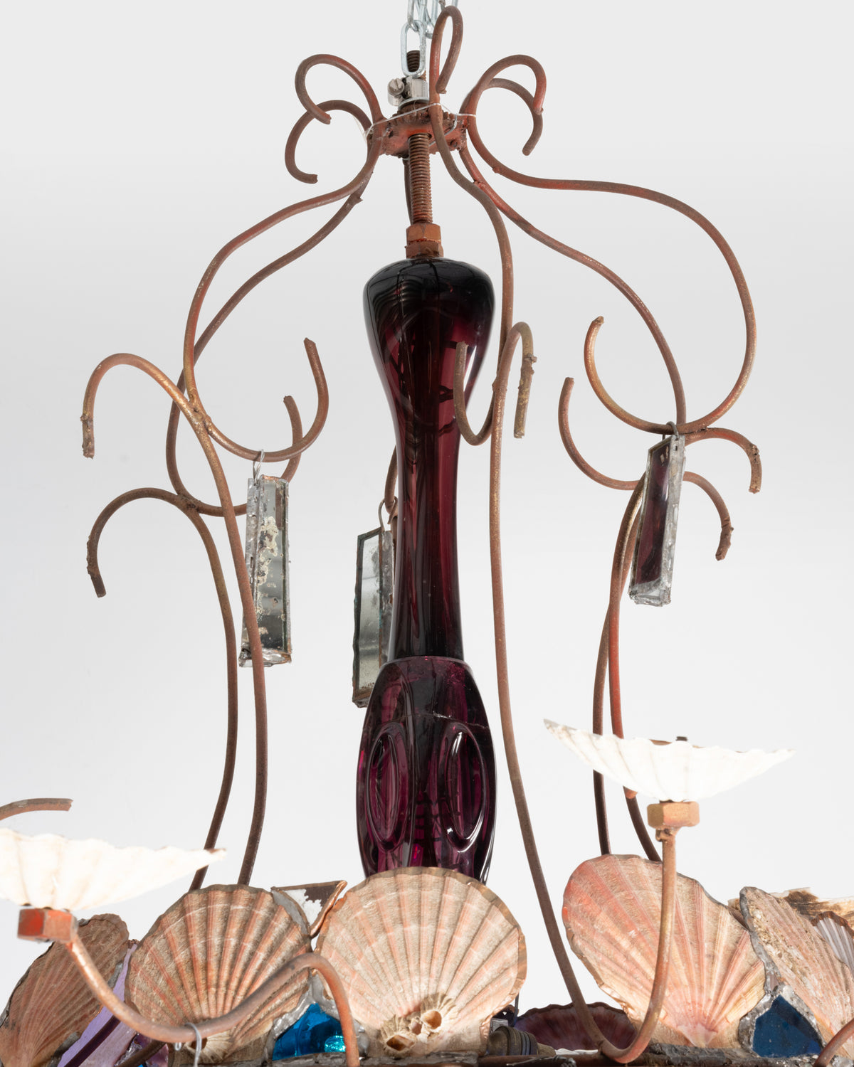 Détail du lustre de Dubreuil et Dixon : fût en verre violet entouré de bras en fer forgé et de coquillages