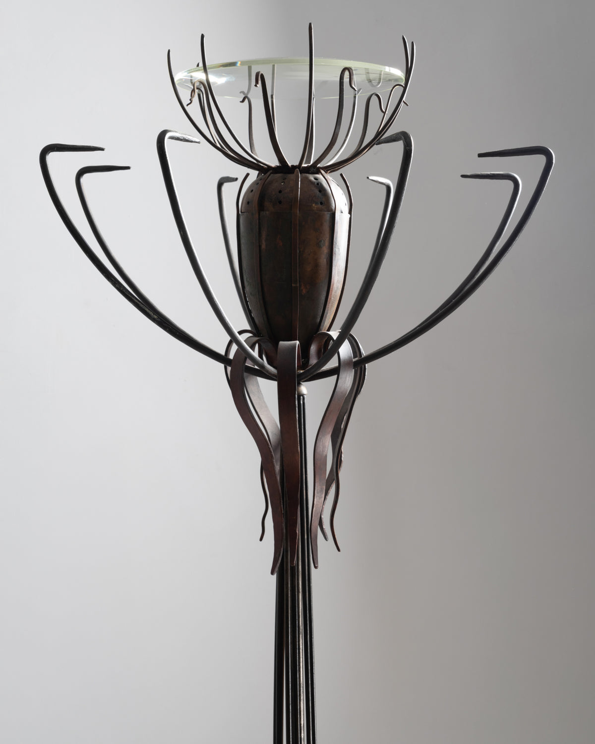 Détail du lampadaire « Pavot » de Dubreuil : capsule de pavot en cuivre entourée de tiges en fer forgé, sous la coupe en verre