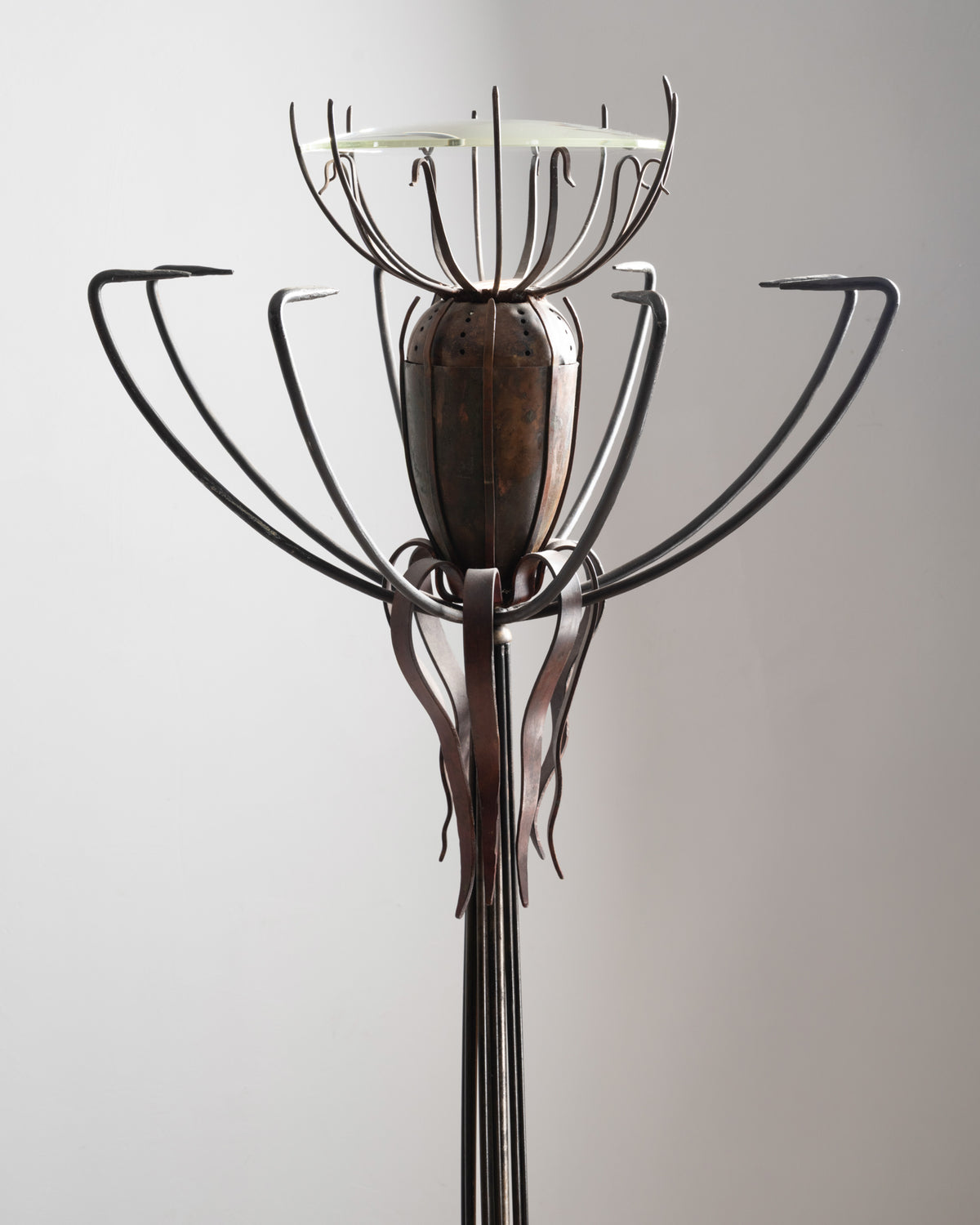 Détail du lampadaire « Pavot » de Dubreuil : tiges en fer forgé recourbées autour de la capsule en cuivre