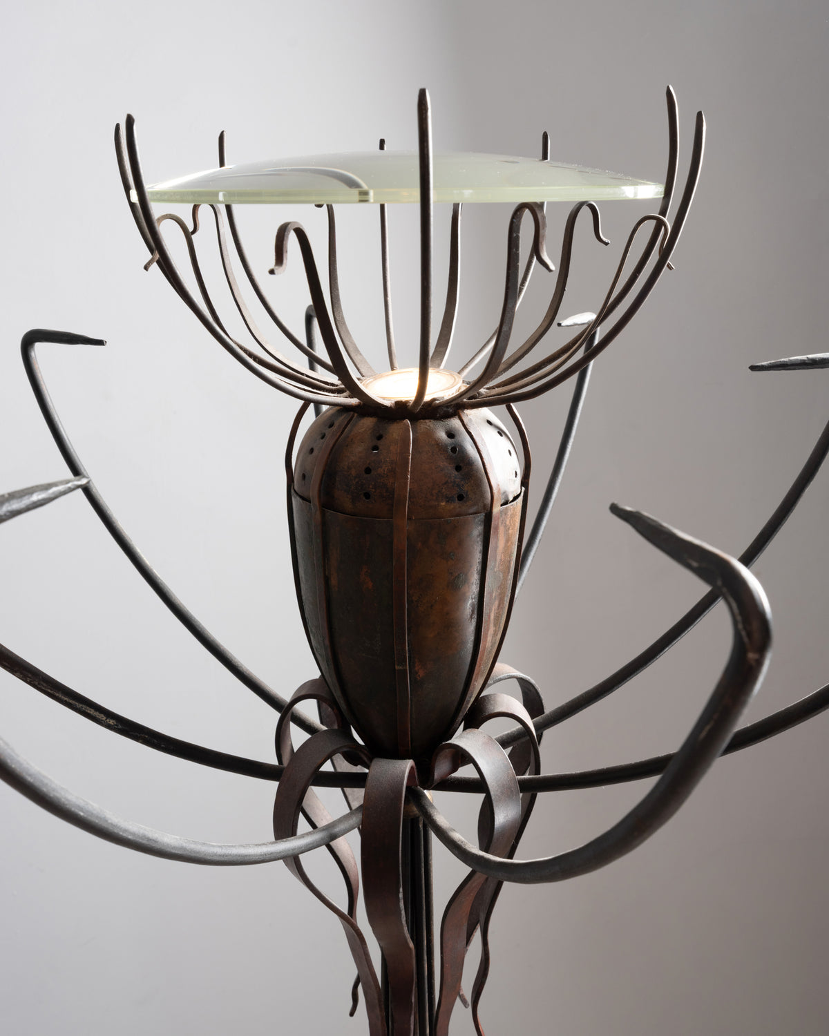 Détail du lampadaire « Pavot » de Dubreuil : capsule en cuivre perforée sous la coupe en verre, éclairée de l'intérieur