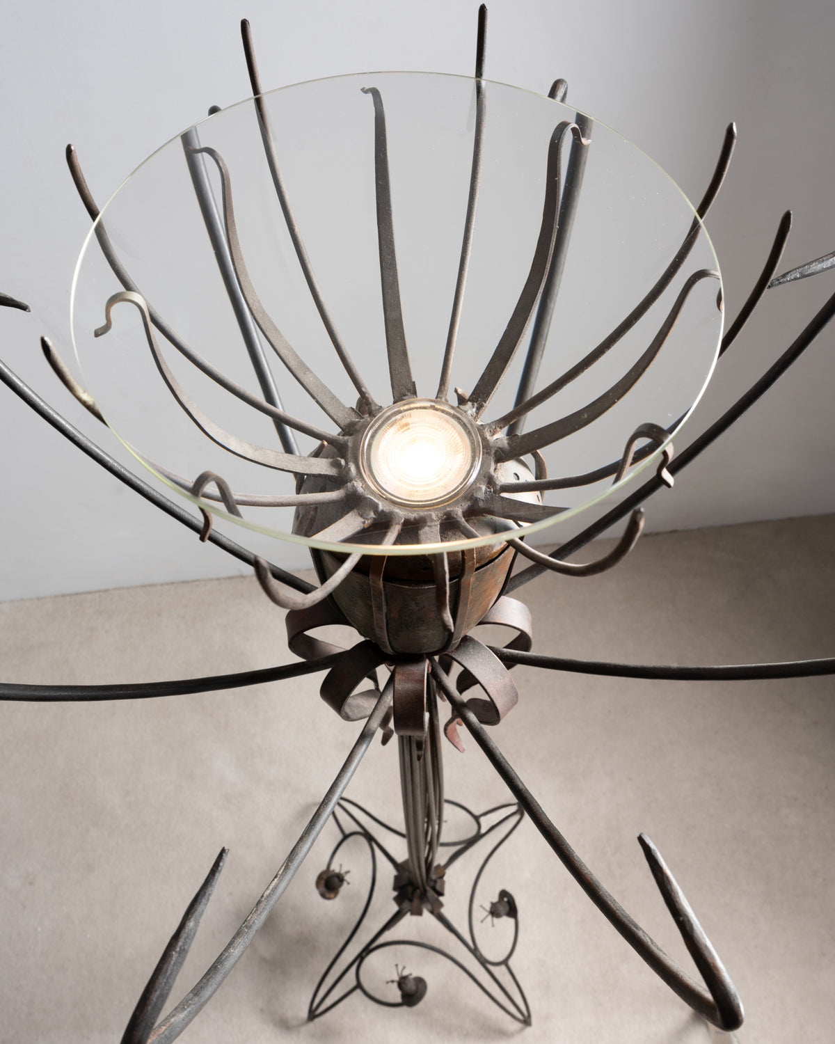 Vue plongeante sur la coupe en verre du lampadaire « Pavot » de Dubreuil, avec l'ampoule au centre des tiges en fer forgé