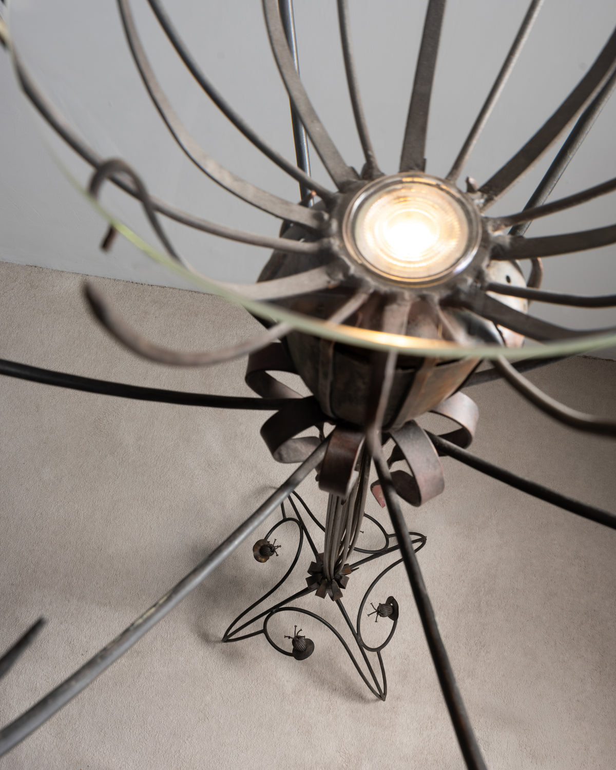 Vue plongeante sur la coupe en verre et l'ampoule du lampadaire « Pavot » de Dubreuil, avec le pied en fer forgé en dessous