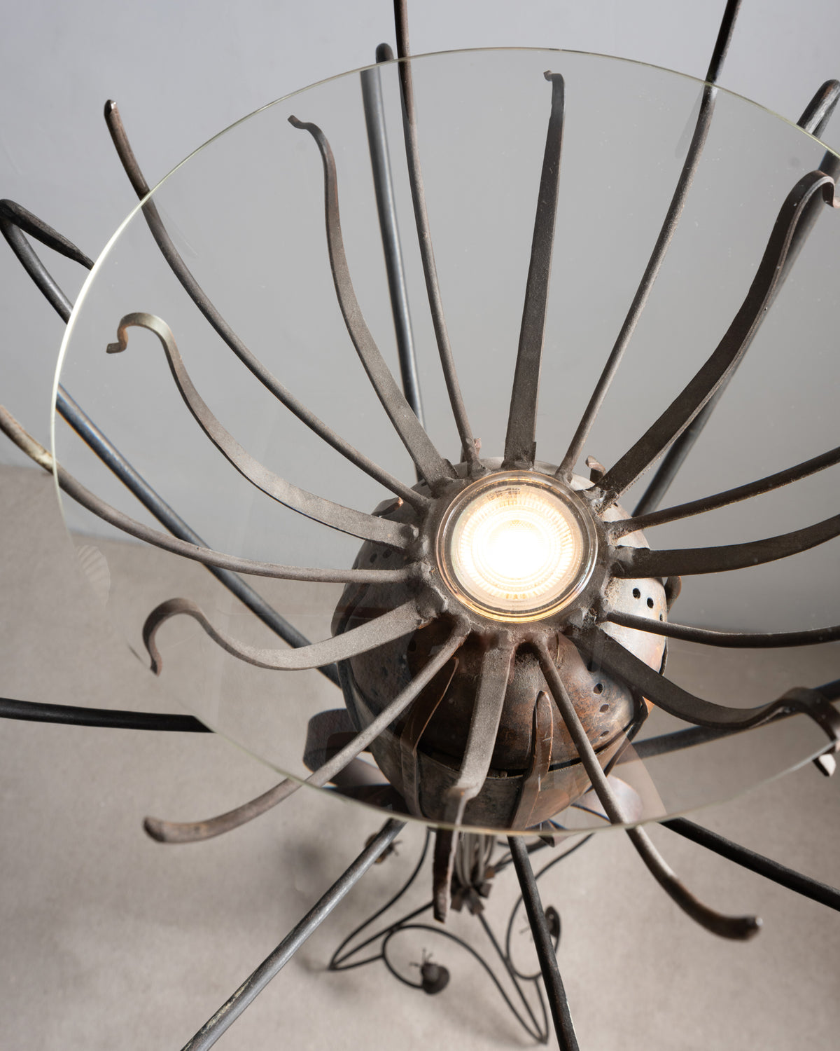 Gros plan sur l'ampoule, la coupe en verre et les tiges rayonnantes du lampadaire « Pavot » de Dubreuil